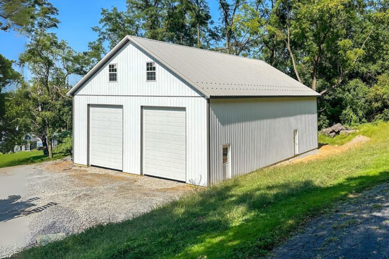 Featured Project 6 Corner of White Pole barn garage with view of two garage doors and attic windows